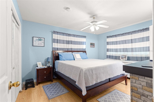 bedroom with a closet, light hardwood / wood-style floors, and ceiling fan