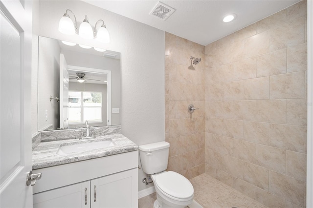 bathroom with vanity, tiled shower, toilet, and ceiling fan