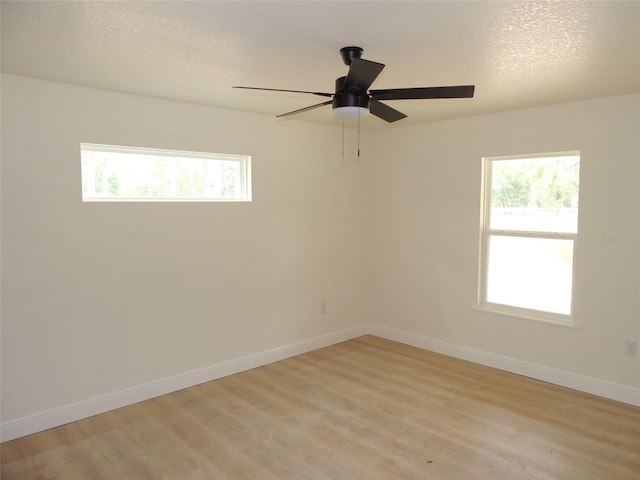 empty room featuring light wood-type flooring, a textured ceiling, and ceiling fan