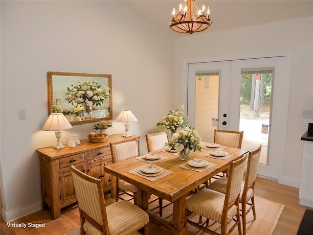 dining space with an inviting chandelier, light wood-type flooring, and french doors