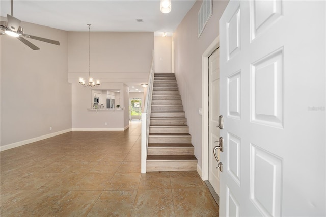 stairs featuring a towering ceiling and ceiling fan with notable chandelier