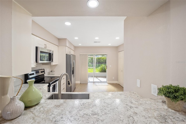 kitchen featuring light stone countertops, sink, stainless steel appliances, and white cabinets