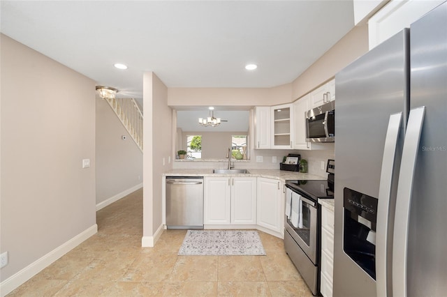 kitchen featuring a notable chandelier, sink, light stone counters, appliances with stainless steel finishes, and white cabinetry