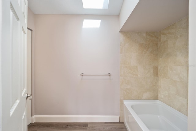 bathroom featuring a skylight, hardwood / wood-style floors, and a tub