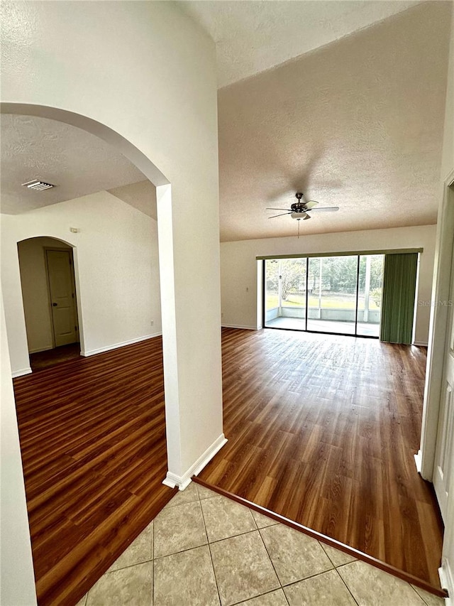 spare room with ceiling fan, hardwood / wood-style flooring, a textured ceiling, and vaulted ceiling