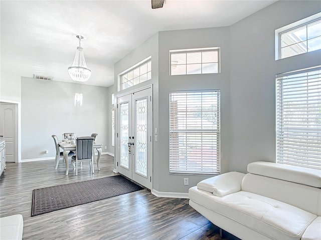 entryway with lofted ceiling, a notable chandelier, french doors, and dark hardwood / wood-style flooring