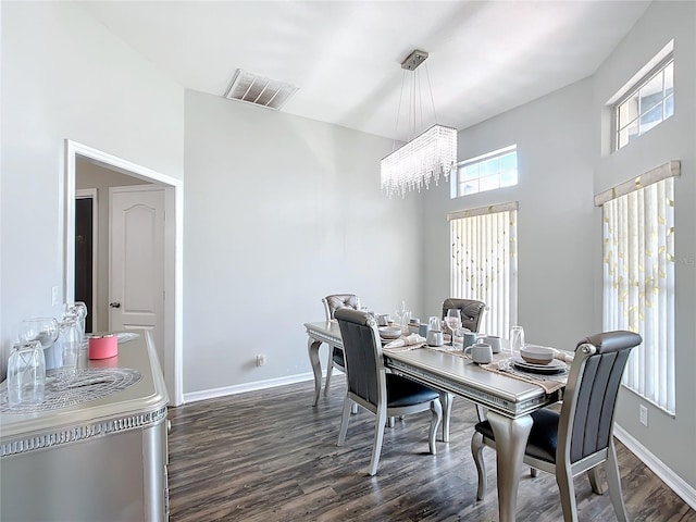 dining space featuring a towering ceiling, an inviting chandelier, and dark hardwood / wood-style flooring