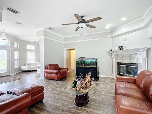 living room featuring wood-type flooring, a fireplace, crown molding, and ceiling fan