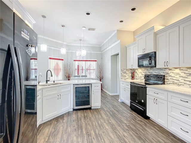 kitchen featuring white cabinets, sink, ornamental molding, beverage cooler, and black appliances