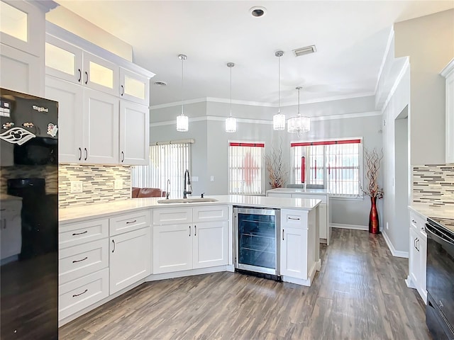 kitchen featuring black appliances, beverage cooler, sink, pendant lighting, and white cabinetry