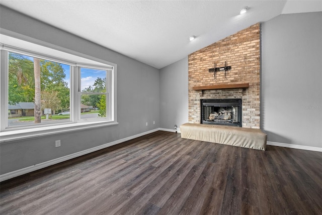 unfurnished living room with lofted ceiling, a brick fireplace, a textured ceiling, and dark hardwood / wood-style flooring