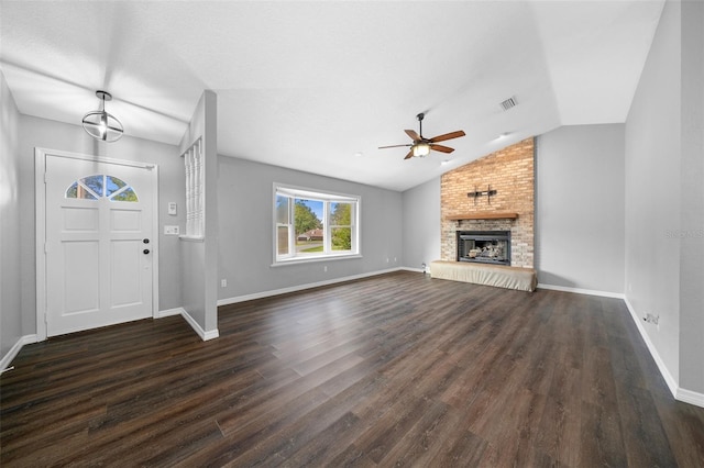 unfurnished living room with dark wood-type flooring, a large fireplace, vaulted ceiling, and ceiling fan