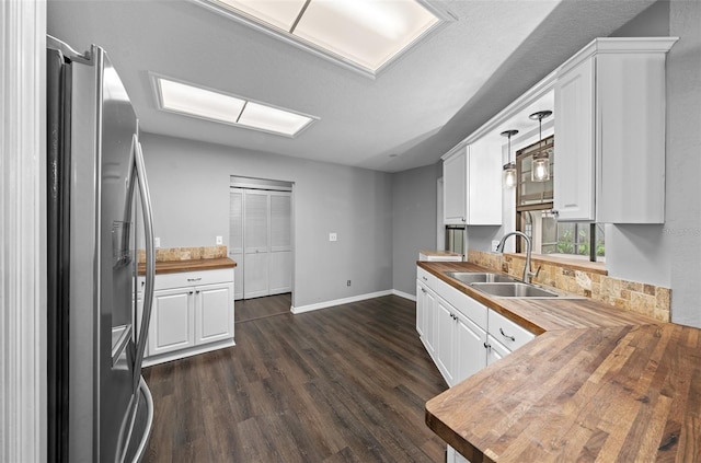 kitchen with sink, stainless steel fridge with ice dispenser, white cabinets, butcher block countertops, and dark hardwood / wood-style flooring