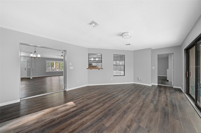 unfurnished living room with a notable chandelier and dark hardwood / wood-style floors