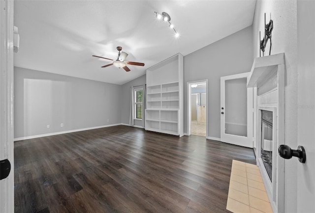 unfurnished living room featuring dark wood-type flooring, vaulted ceiling, built in shelves, and ceiling fan