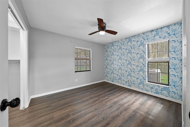 empty room featuring ceiling fan, a textured ceiling, and dark hardwood / wood-style flooring