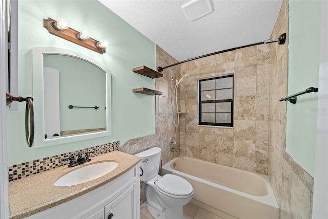 full bathroom with a textured ceiling, toilet, tiled shower / bath, vanity, and tile patterned flooring