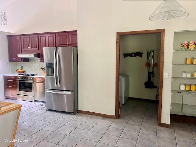 kitchen with washer / dryer, ventilation hood, light tile patterned flooring, appliances with stainless steel finishes, and decorative light fixtures