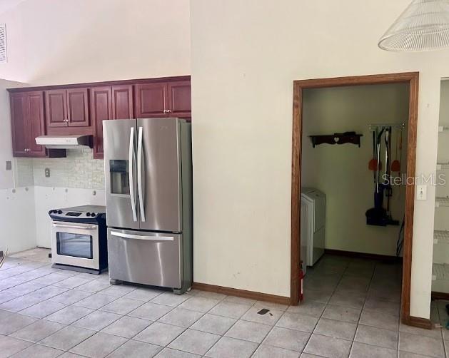 kitchen featuring washer and clothes dryer, stainless steel appliances, light tile patterned floors, and tasteful backsplash