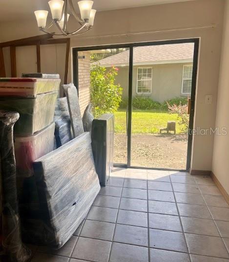 doorway to outside featuring a notable chandelier, tile patterned flooring, and a wealth of natural light