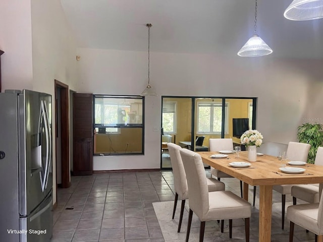 dining area featuring a high ceiling and dark tile patterned flooring