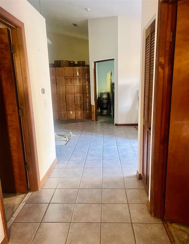 hall featuring lofted ceiling and light tile patterned floors