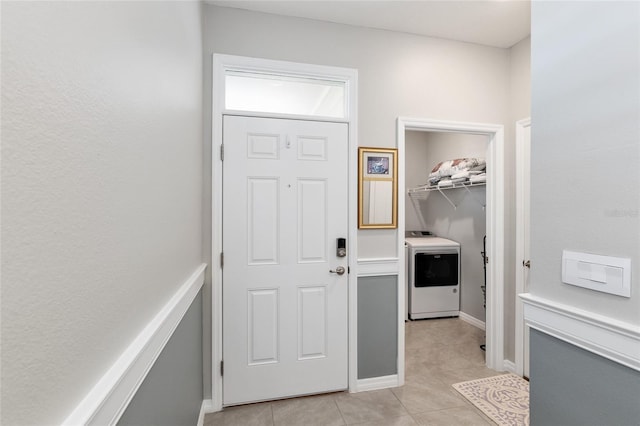 clothes washing area with washer / dryer and light tile patterned floors