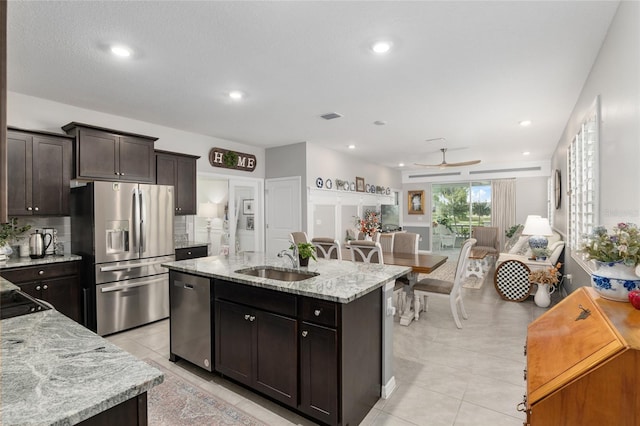 kitchen featuring a center island with sink, sink, dark brown cabinetry, appliances with stainless steel finishes, and ceiling fan