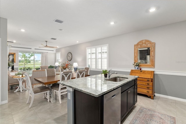 kitchen with dishwasher, a kitchen island with sink, sink, light stone counters, and ceiling fan