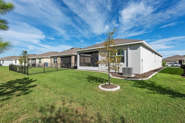 rear view of house featuring a yard, a sunroom, and central AC