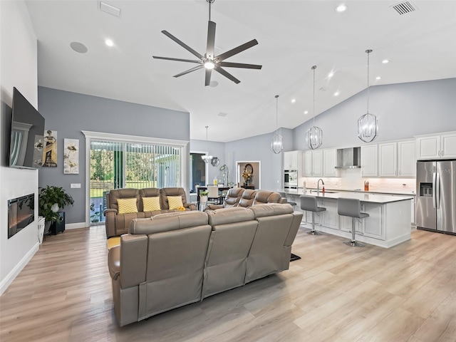 living room with ceiling fan, sink, high vaulted ceiling, and light hardwood / wood-style flooring