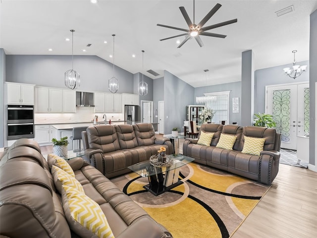 living room featuring light wood-type flooring, high vaulted ceiling, ceiling fan, and sink