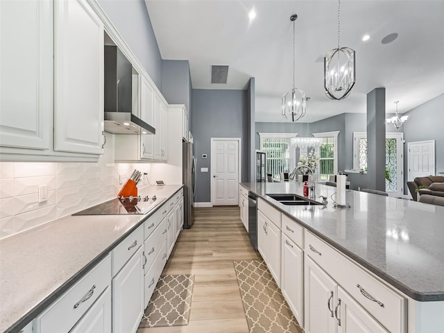 kitchen with sink, wall chimney exhaust hood, stainless steel appliances, light hardwood / wood-style flooring, and white cabinets