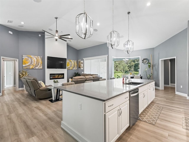 kitchen with stainless steel dishwasher, a kitchen island with sink, sink, light hardwood / wood-style flooring, and white cabinetry