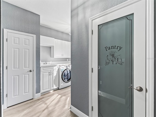 laundry area with cabinets, washer / dryer, light wood-type flooring, and sink