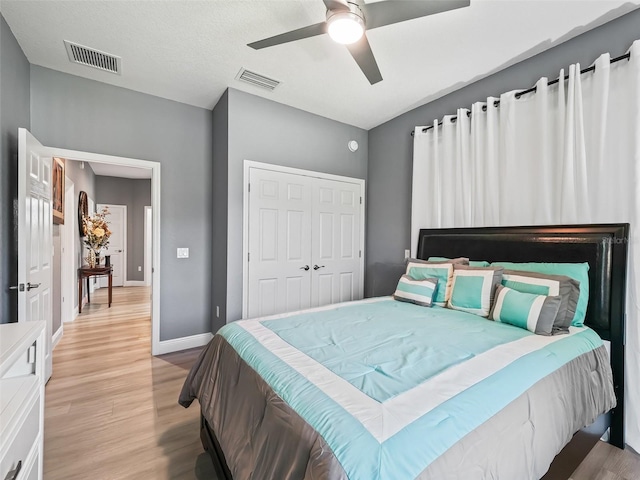 bedroom with a textured ceiling, light wood-type flooring, a closet, and ceiling fan