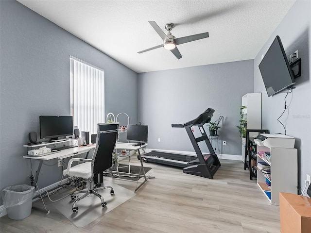 home office featuring ceiling fan, light hardwood / wood-style flooring, and a textured ceiling