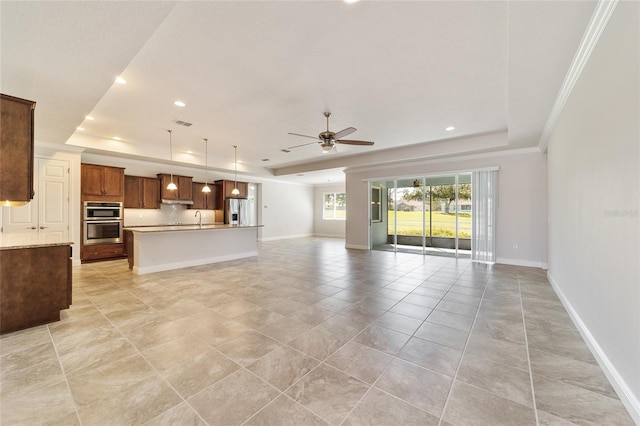 unfurnished living room with crown molding, a tray ceiling, sink, and ceiling fan