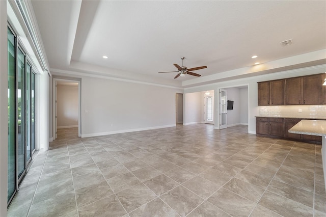 unfurnished living room featuring a raised ceiling, light tile patterned floors, and ceiling fan