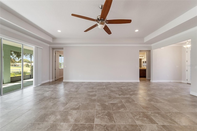 empty room with ceiling fan and a tray ceiling