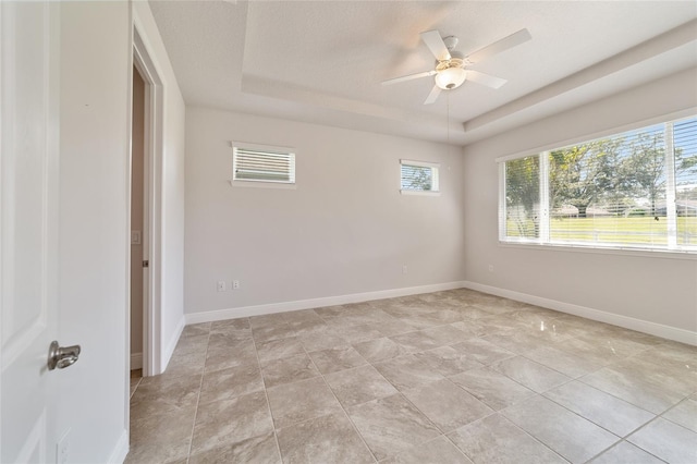 tiled spare room with a tray ceiling, a textured ceiling, and ceiling fan