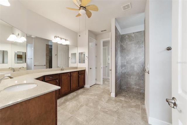 bathroom with tile patterned flooring, ceiling fan, vanity, and tiled shower