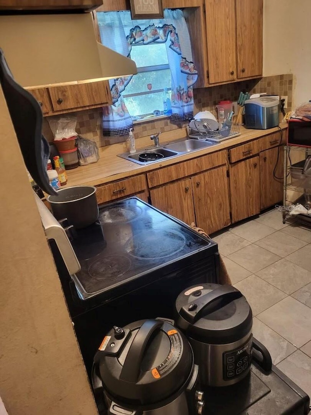 kitchen with light tile patterned flooring, sink, and backsplash