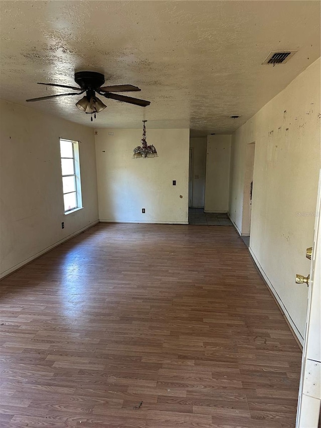 empty room with ceiling fan, wood-type flooring, and a textured ceiling