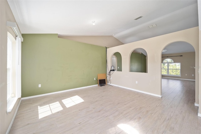 unfurnished room with light wood-type flooring and vaulted ceiling