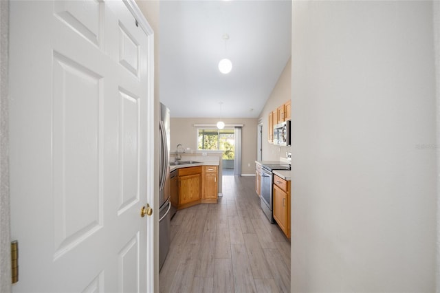 kitchen with light hardwood / wood-style floors, sink, decorative light fixtures, stainless steel appliances, and vaulted ceiling