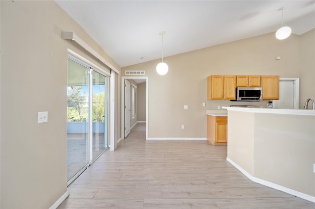 kitchen with light brown cabinets, lofted ceiling, hanging light fixtures, and light hardwood / wood-style flooring