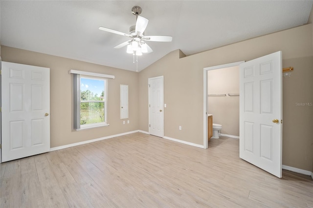 unfurnished bedroom featuring ceiling fan, light hardwood / wood-style flooring, ensuite bath, and vaulted ceiling