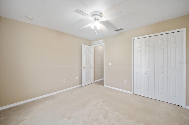 unfurnished bedroom featuring a closet, light colored carpet, and ceiling fan