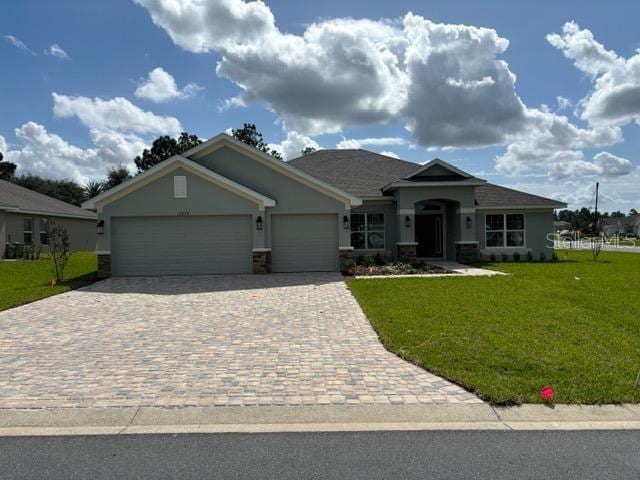 view of front of house featuring an attached garage, a front lawn, stucco siding, and decorative driveway